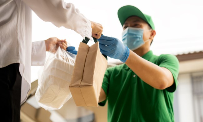 Delivery driver delivering bags of food to a man.