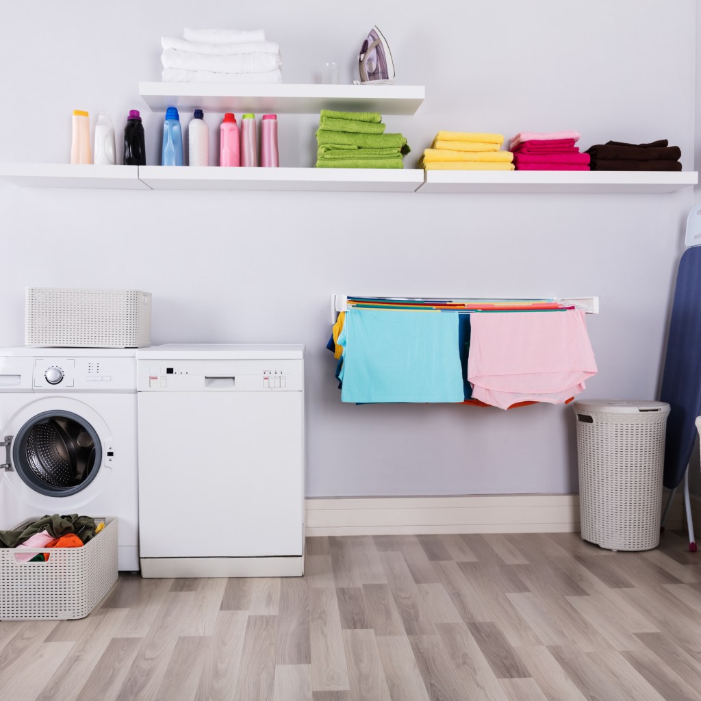Colorful towels and detergents on high-up shelves in laundry room.