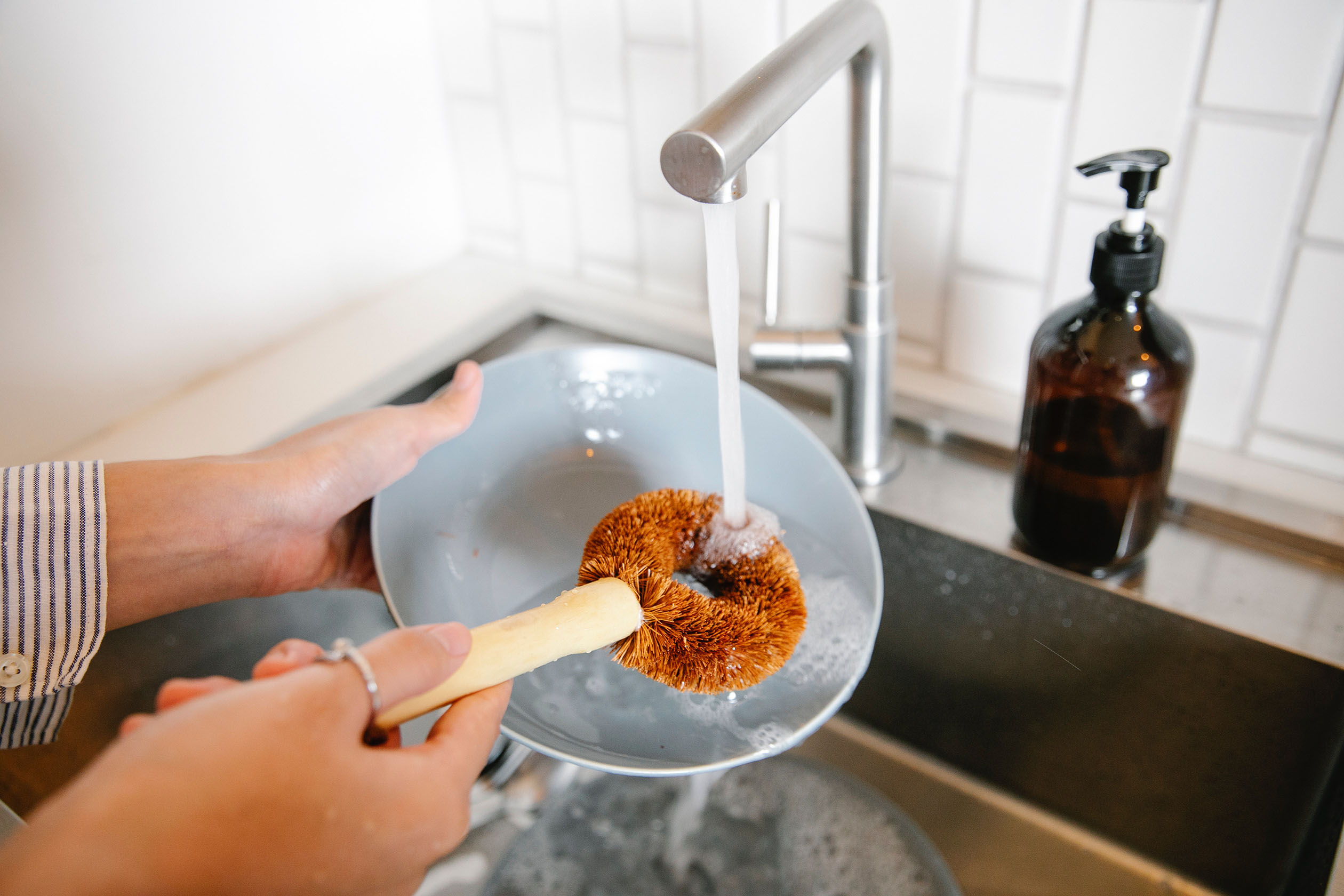 Person washing dishes with a brush
