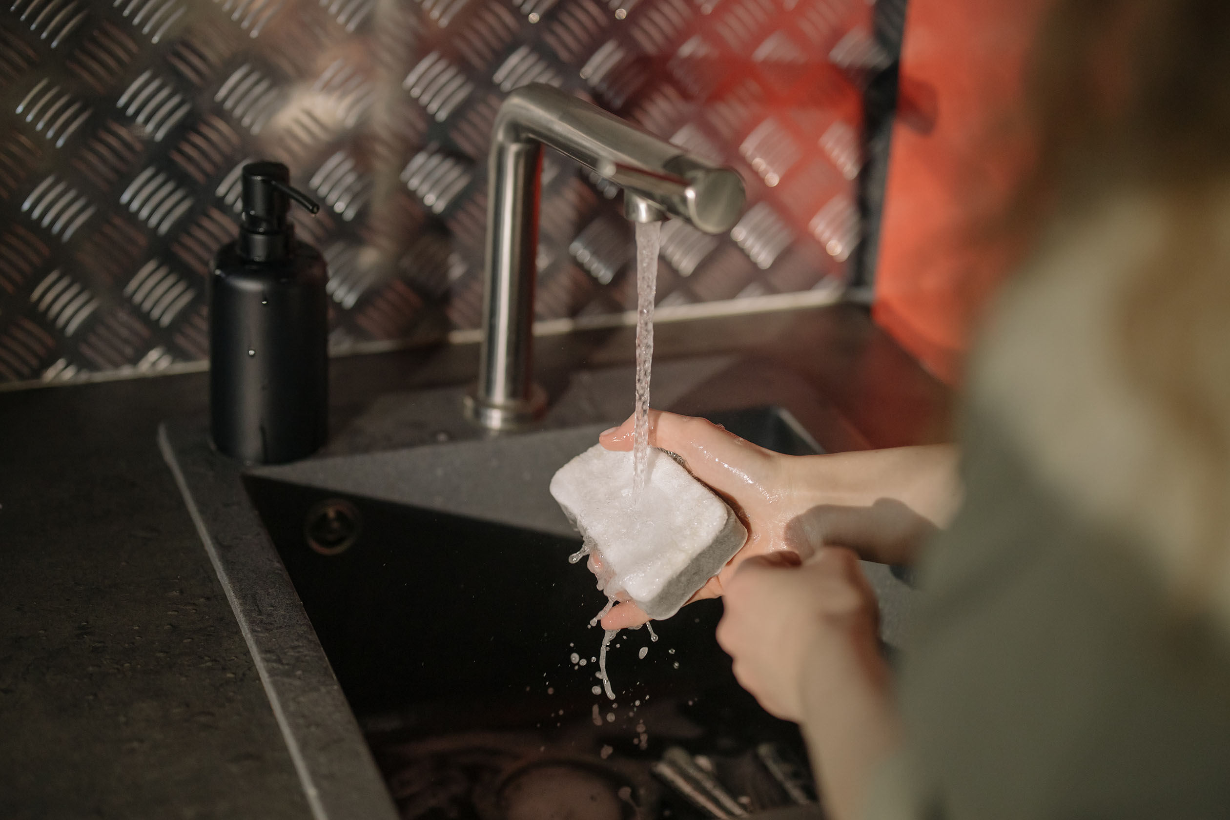 Person washing dishes with a sponge