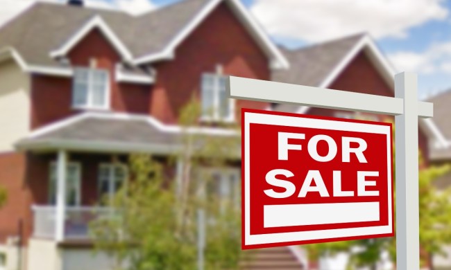 Red house with for sale sign in the front yard