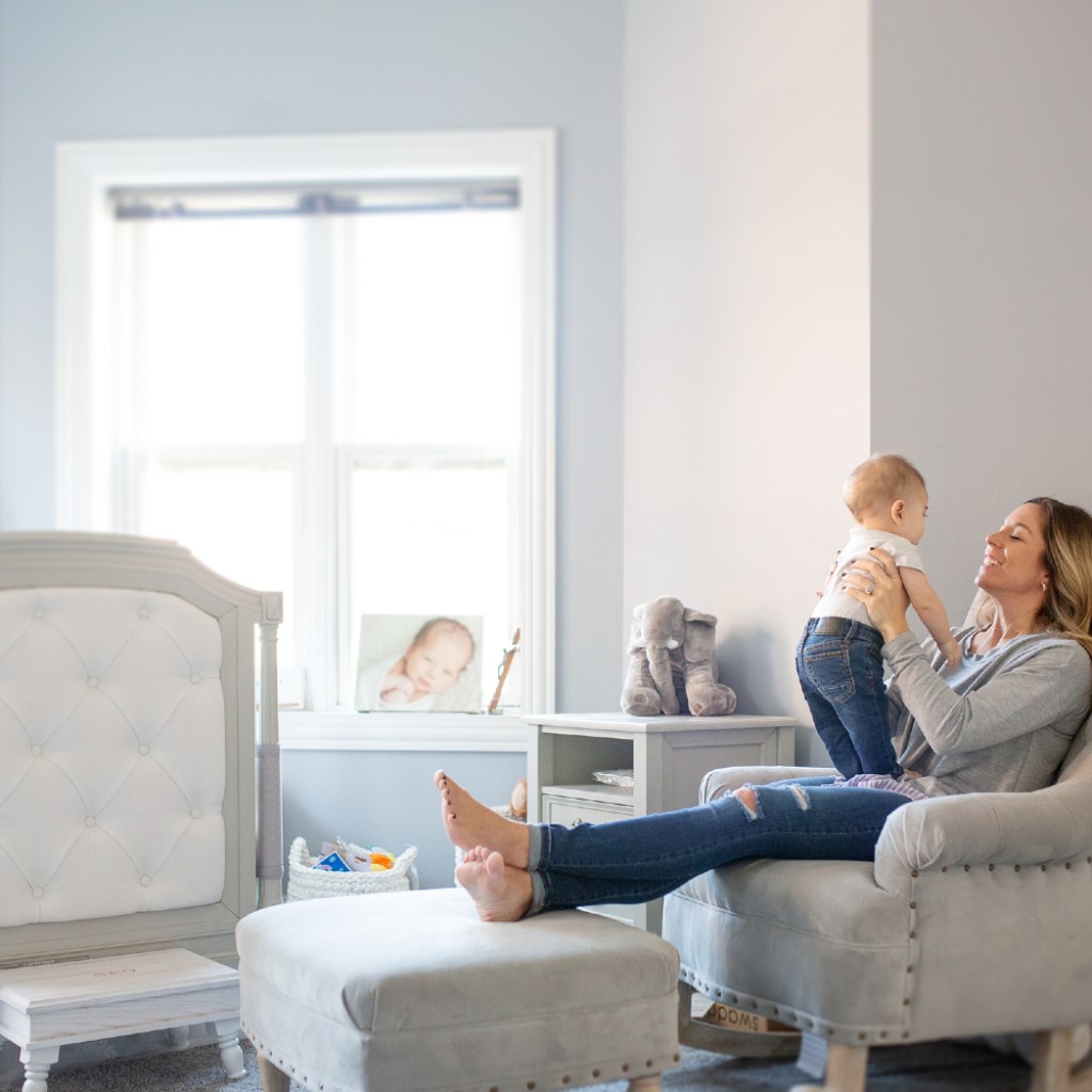 Woman with baby in a gray nursery.