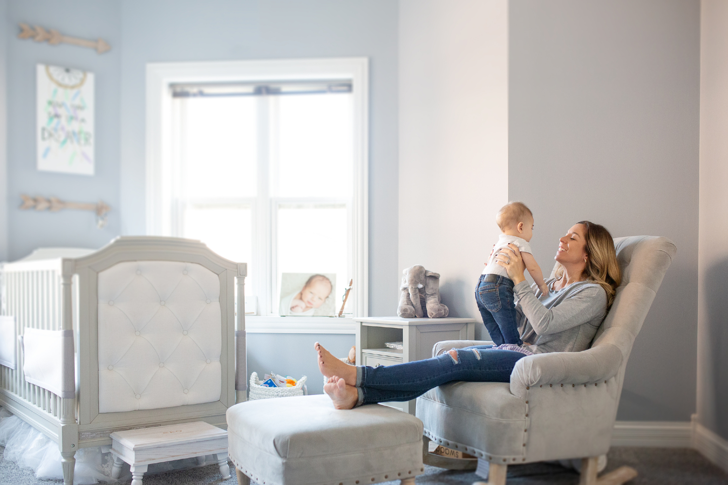 Woman with baby in a gray nursery.
