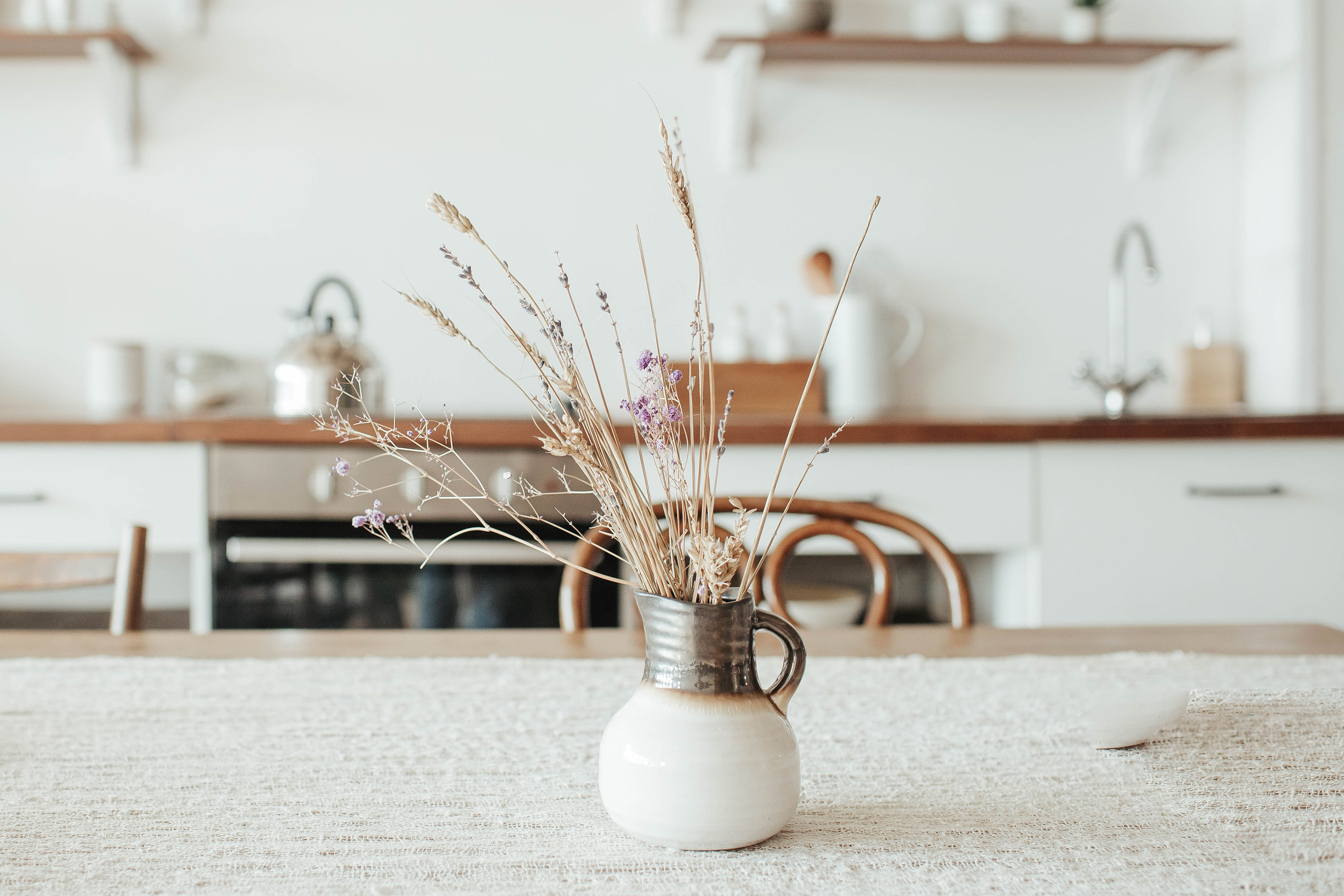 Ceramic jug vase with dried flowers on kitchen counter
