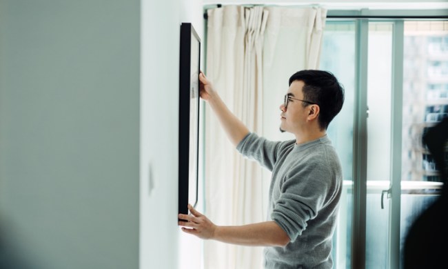expert advice for decorating on a budget young asian man holding picture frame and hanging the painting wall in his newly ref