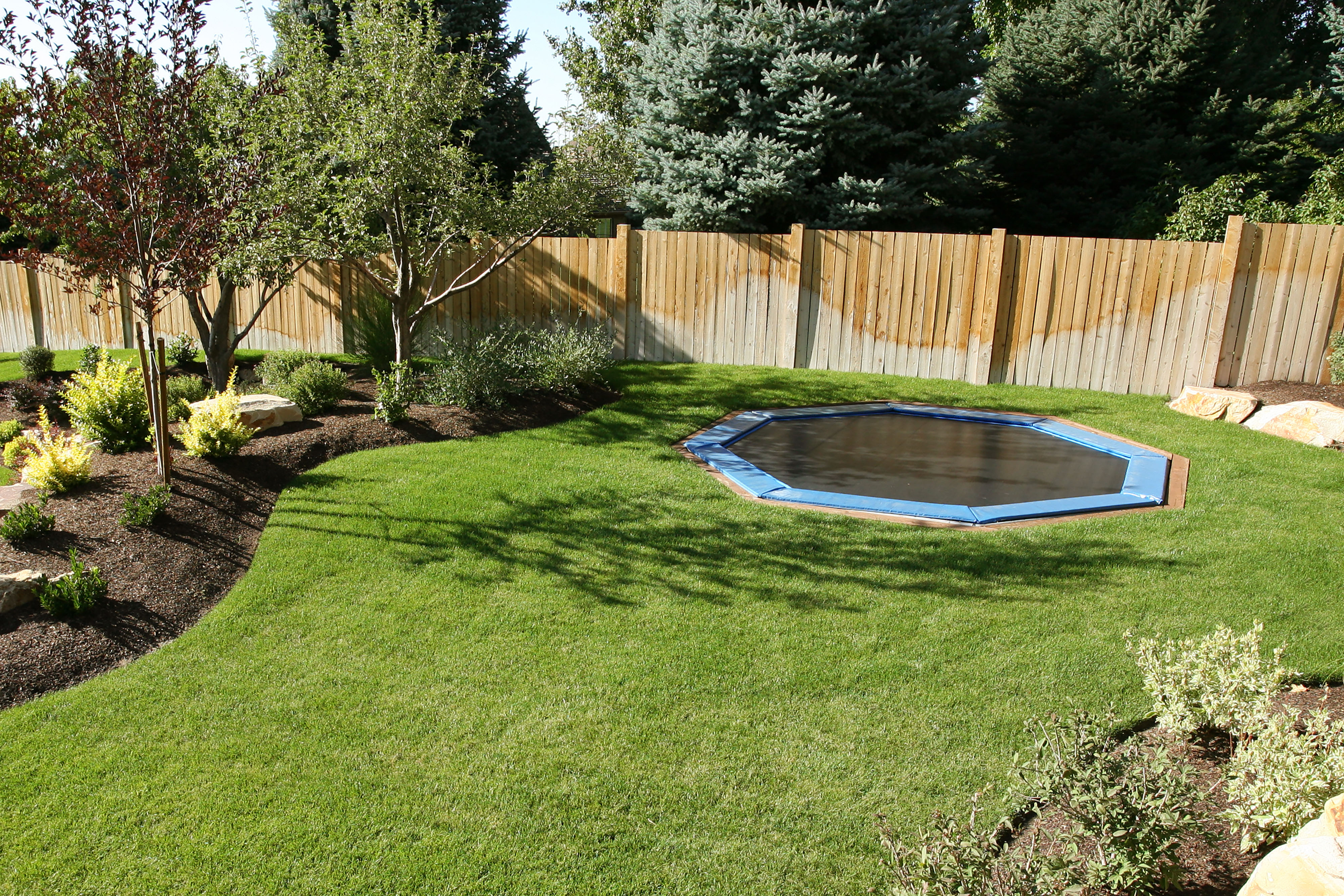 Landscaped backyard with in-ground trampoline