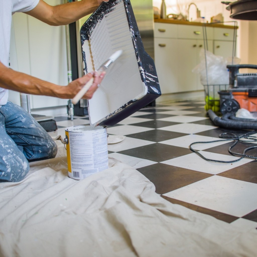 Person painting kitchen tile with DIY method