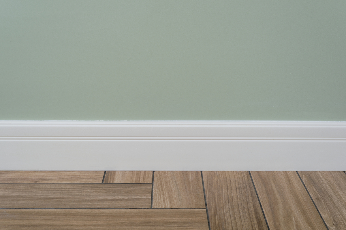 Sage green walls with white baseboard and hardwood floor