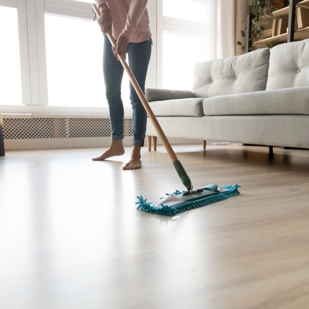 Woman with bare feet cleaning laminate floor with swiffer style mop