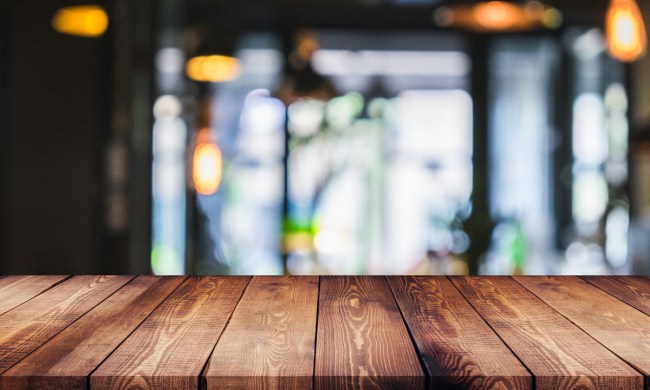 Close-up of rustic wood surface with window and lights in background