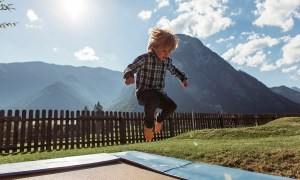 Small child jumping on a trampoline with mountains in the background