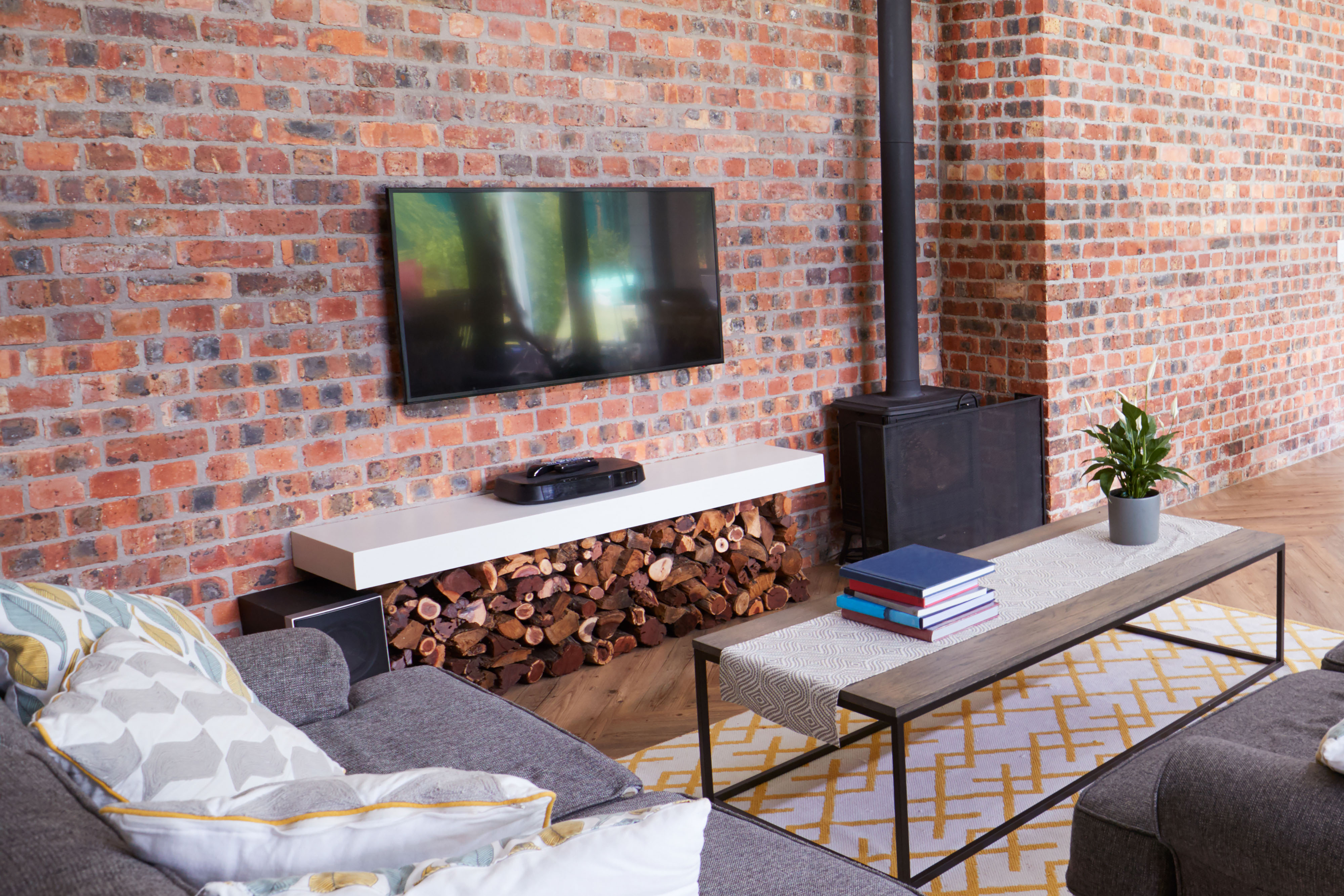 TV mounted on exposed brick wall with a sitting area