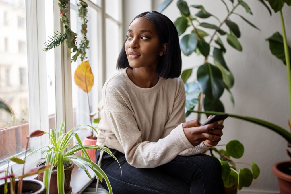 Woman sitting at home surrounded by plants