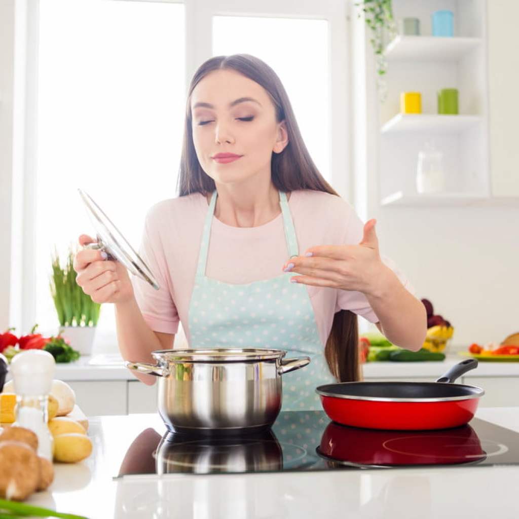 woman smelling cooking in kitchen