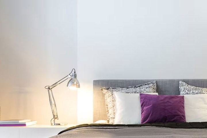 Desk lamp next to bed with gray and purple bedding