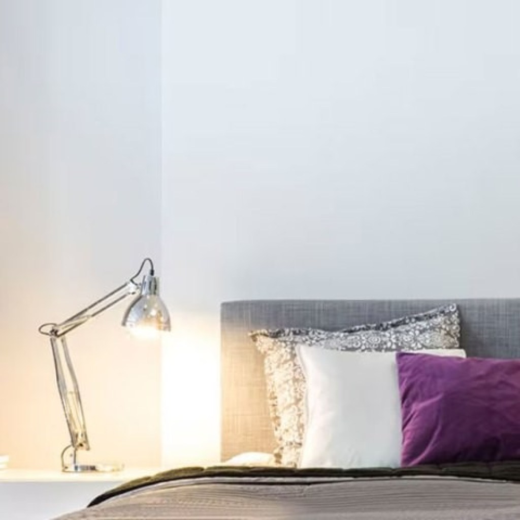 Desk lamp next to bed with gray and purple bedding