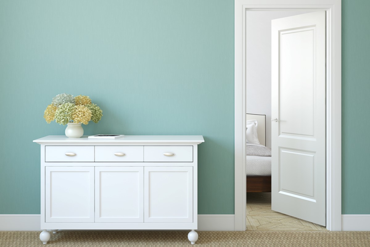 Light blue wall with white bedroom door, trim, and console table