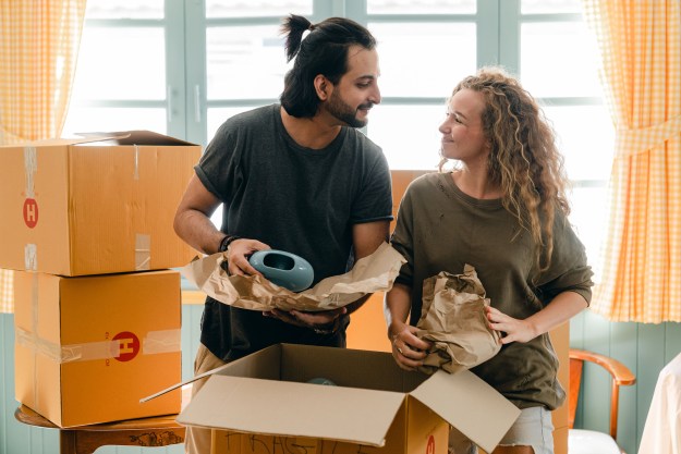 Couple packing moving boxes together