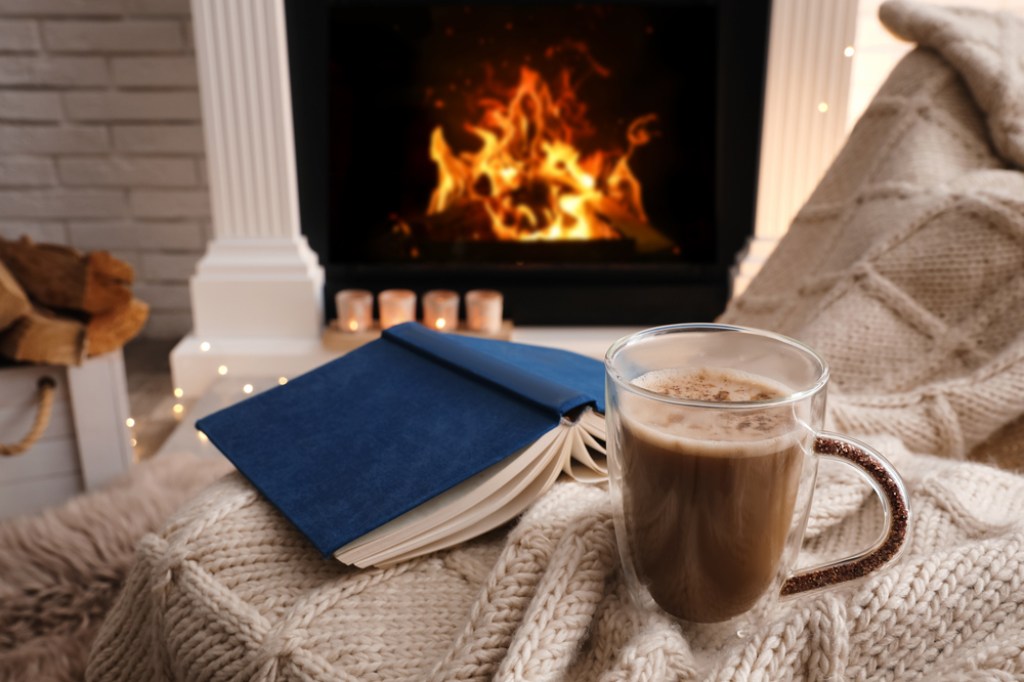 Cozy by fireplace with book, hot chocolate, and blanket