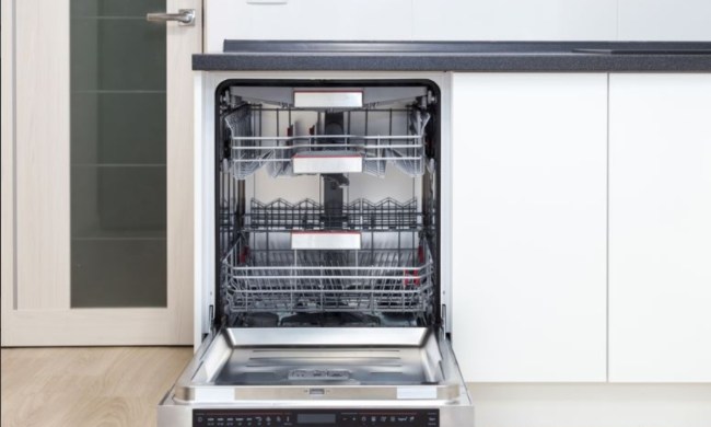 Open dishwasher that is clean inside built into to kitchen cabinets