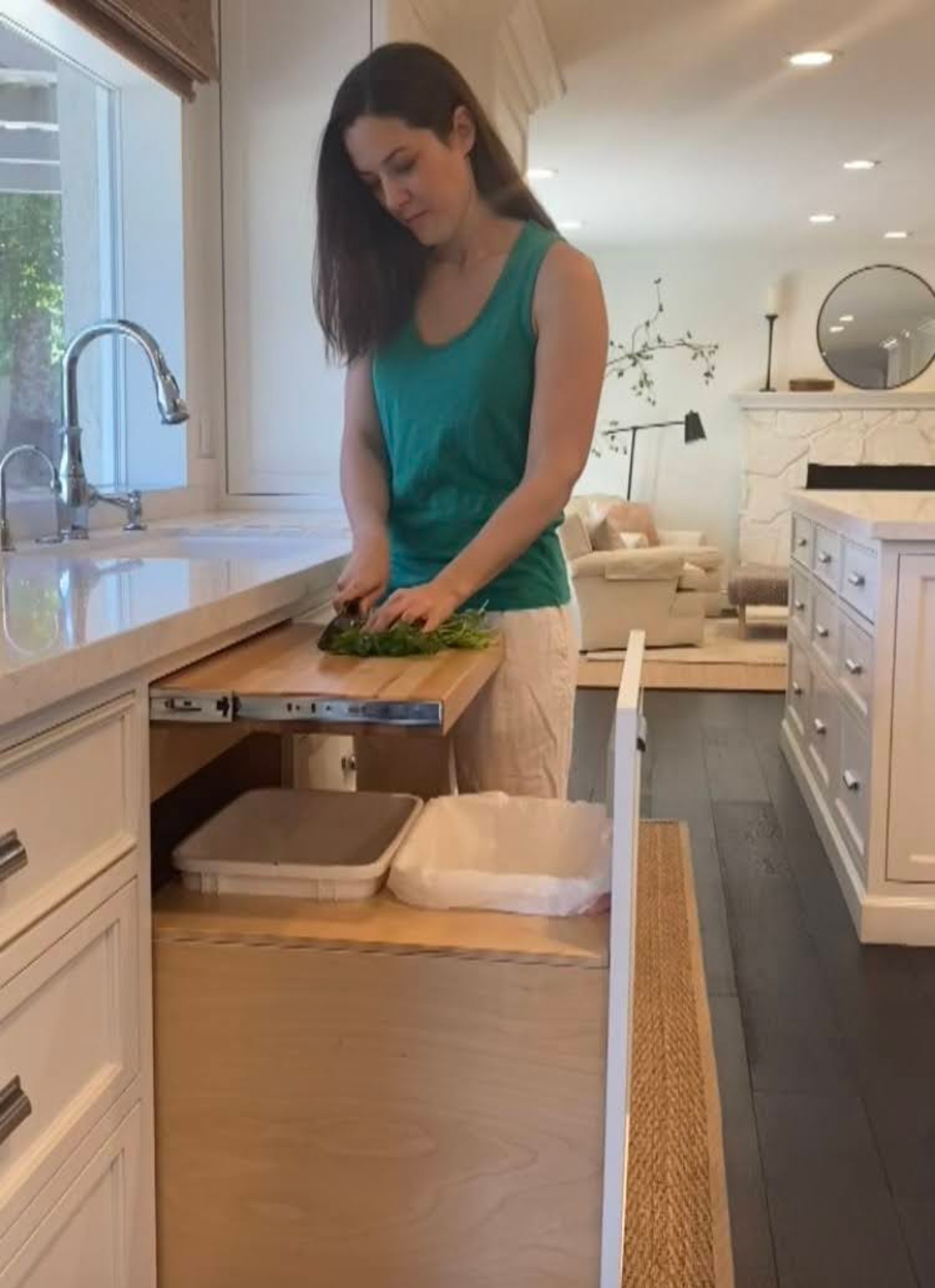 Woman cutting vegetables on pull-out cabinet cutting board in kitchen