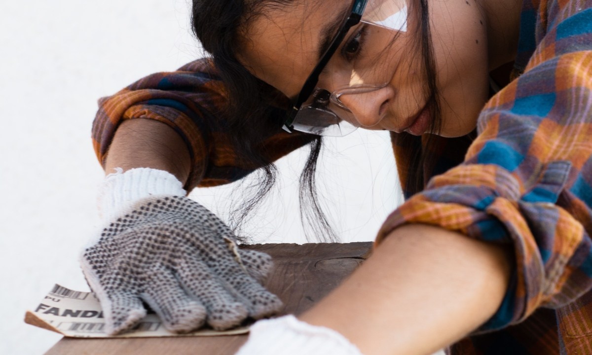 Woman using sand paper to sand wood