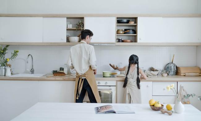 Father and daughter cooking in front of pvc kitchen cabinets