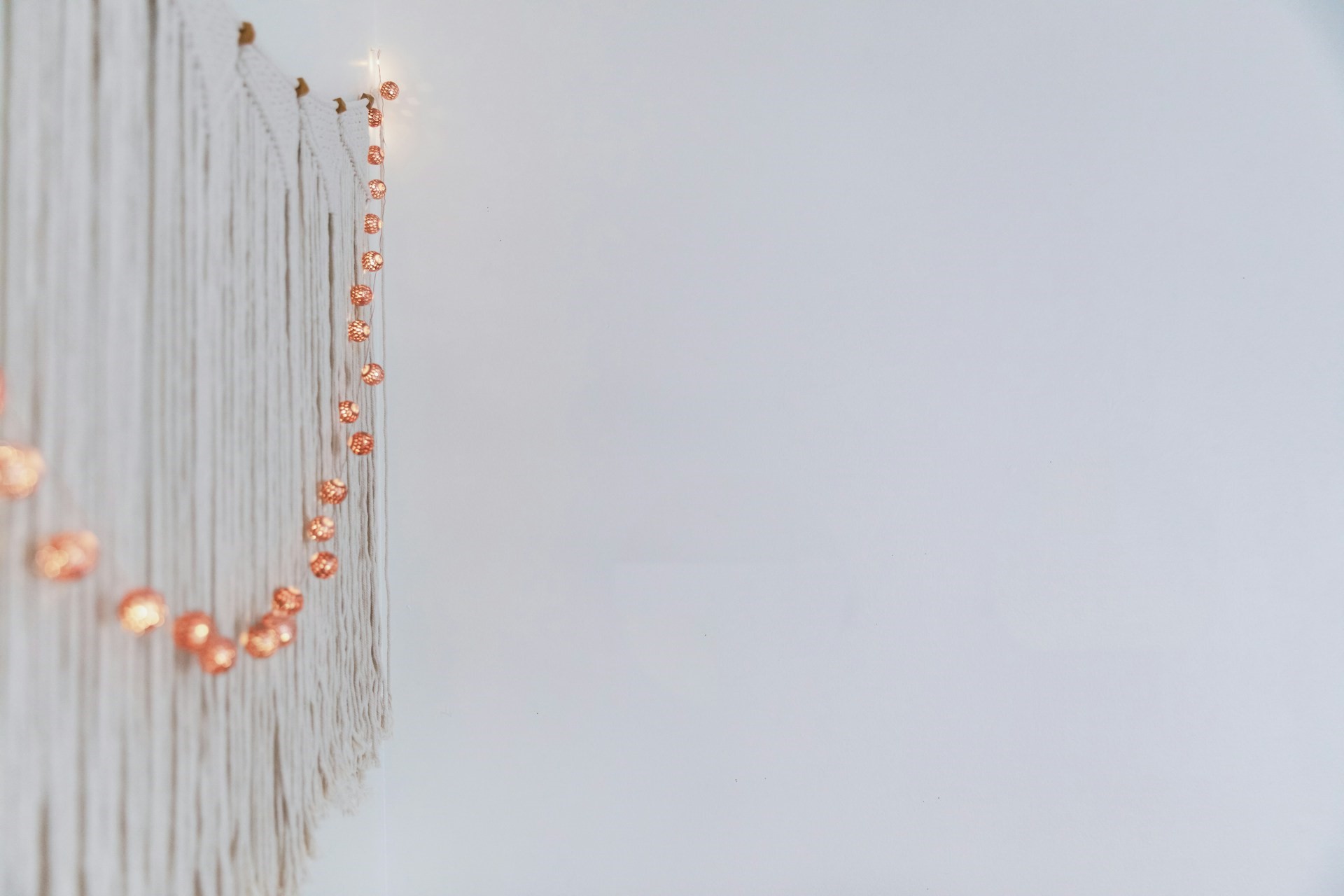 white macrame wall with copper colored lights