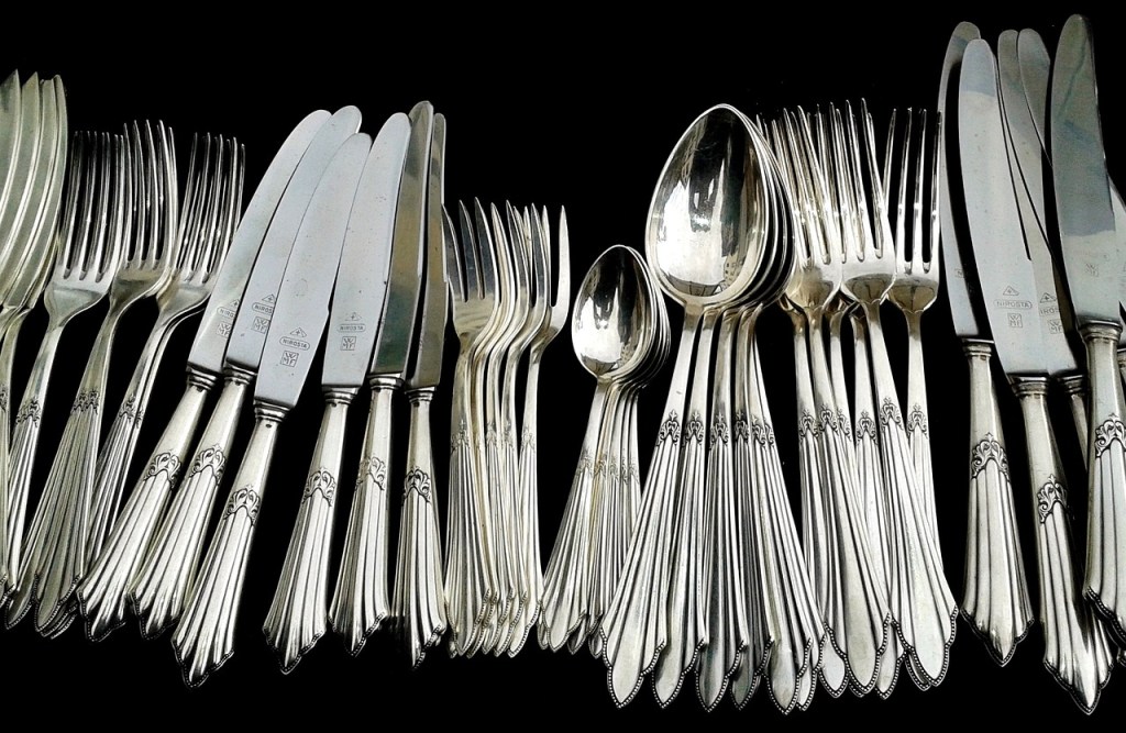 piles of silverware on a black surface