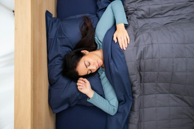 Woman sleeping with gray blanket and navy sheets