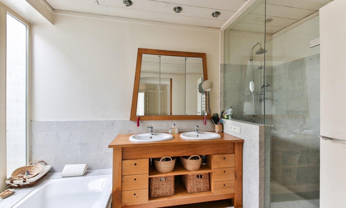 Wood bathroom mirror and vanity with tub and glass shower