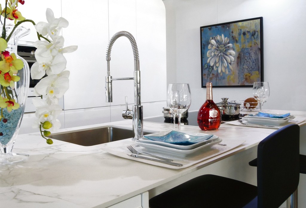 White countertop with curved sink faucet and bar stools