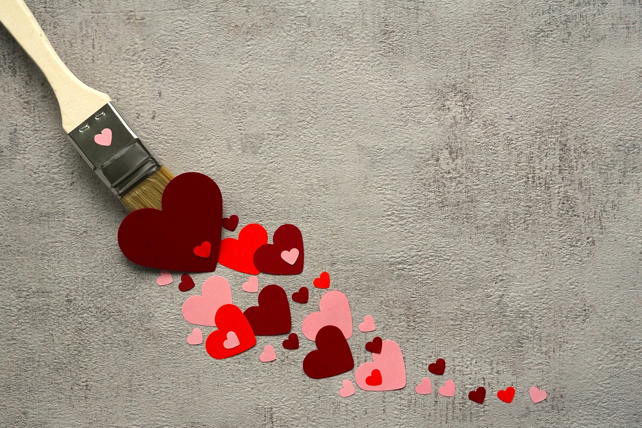 Paintbrush with paper hearts on gray carpet