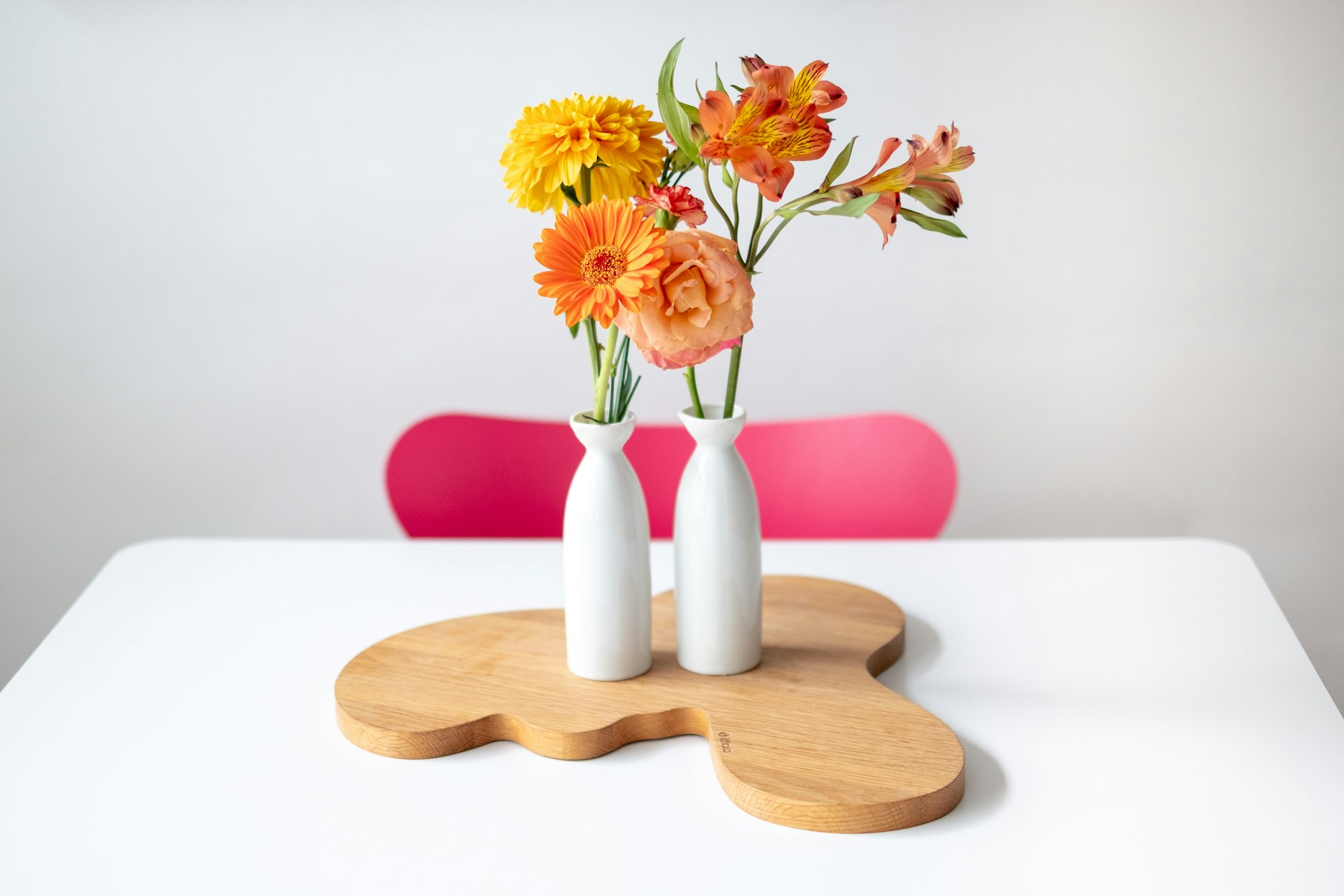 Yellow flowers on a white table with a hot pink chair