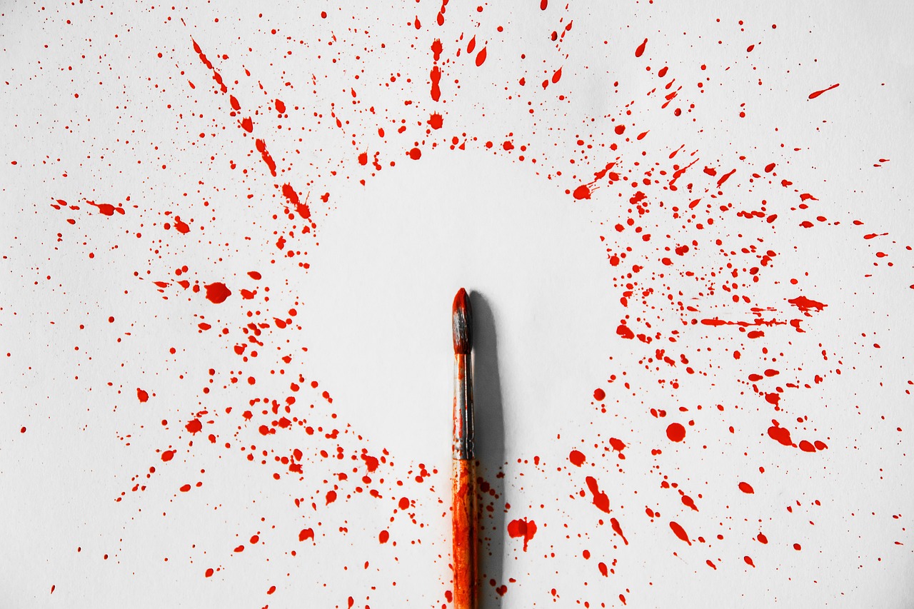 Small paint brush surrounded by red paint splash