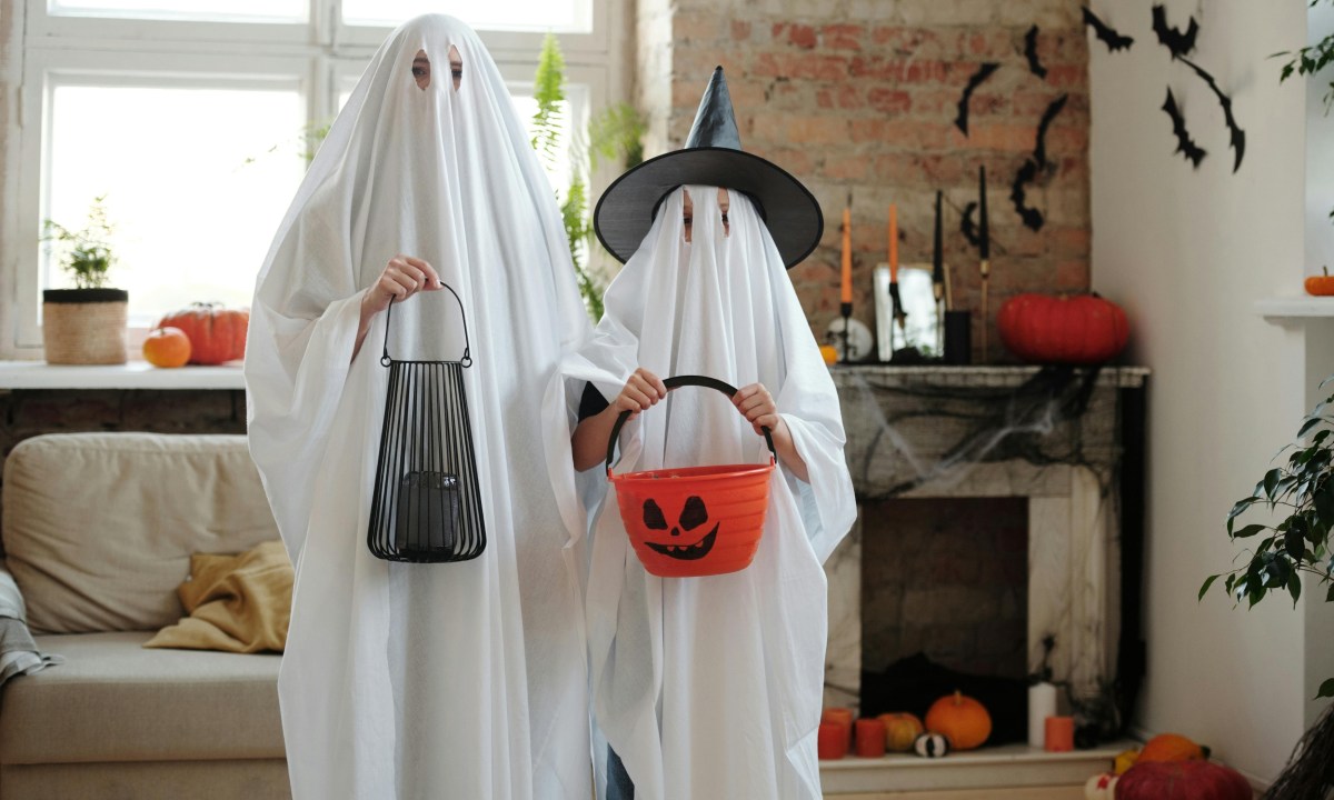 kids wearing ghost halloween costumes in decorated living room