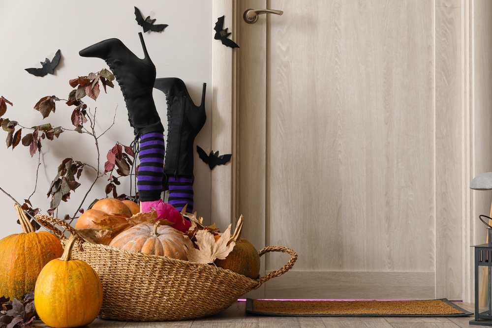 Front door decorated with witch legs and pumpkins