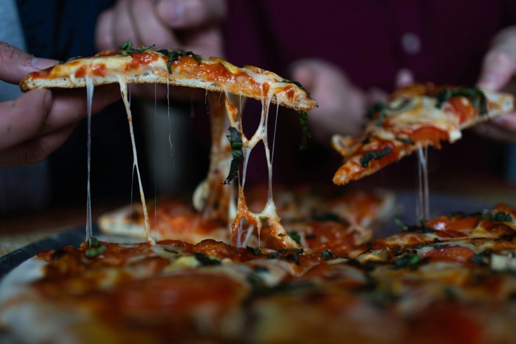 Lifting pizza slices from pie