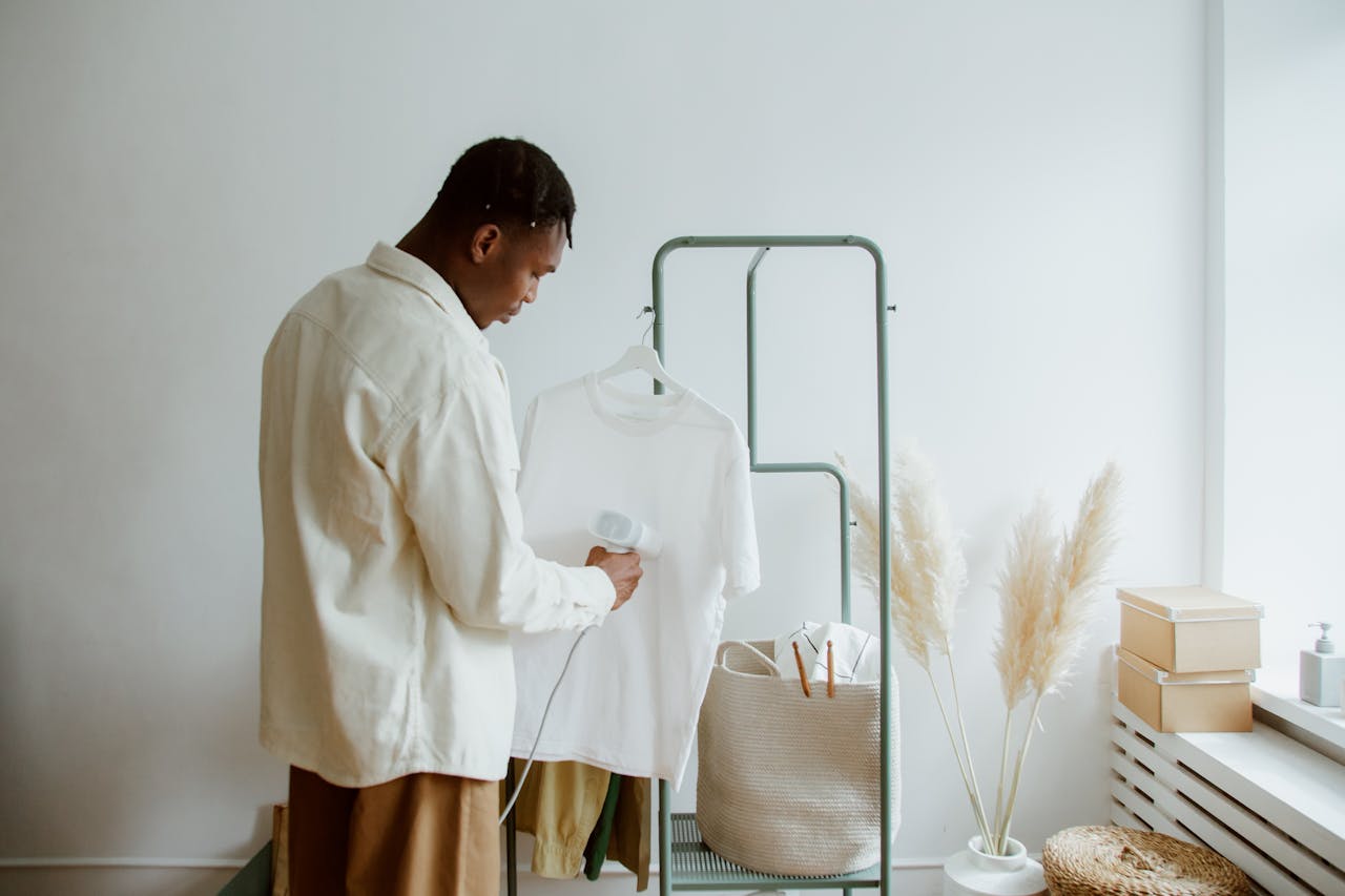 Man steaming a white shirt with a clothes steamer