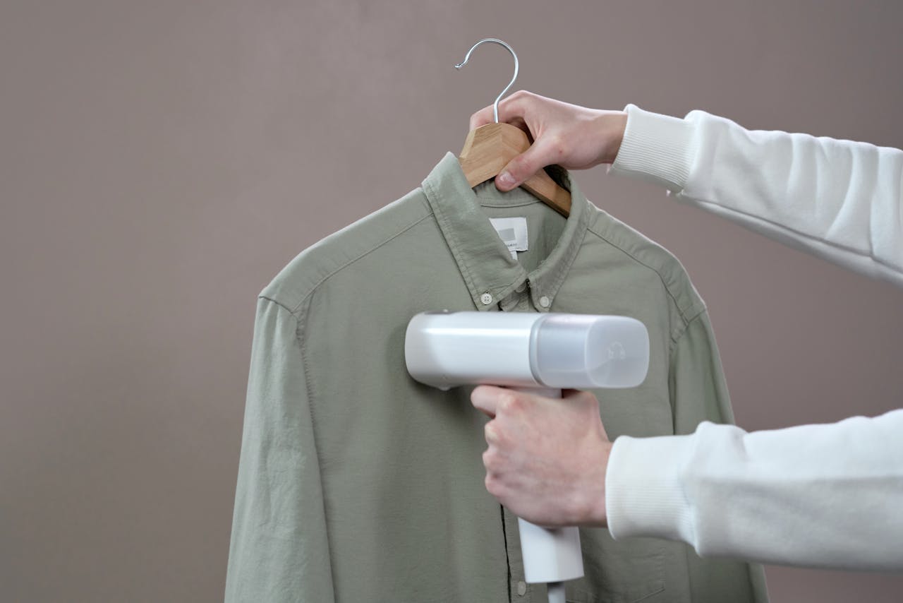 Person using a steamer on a button down shirt