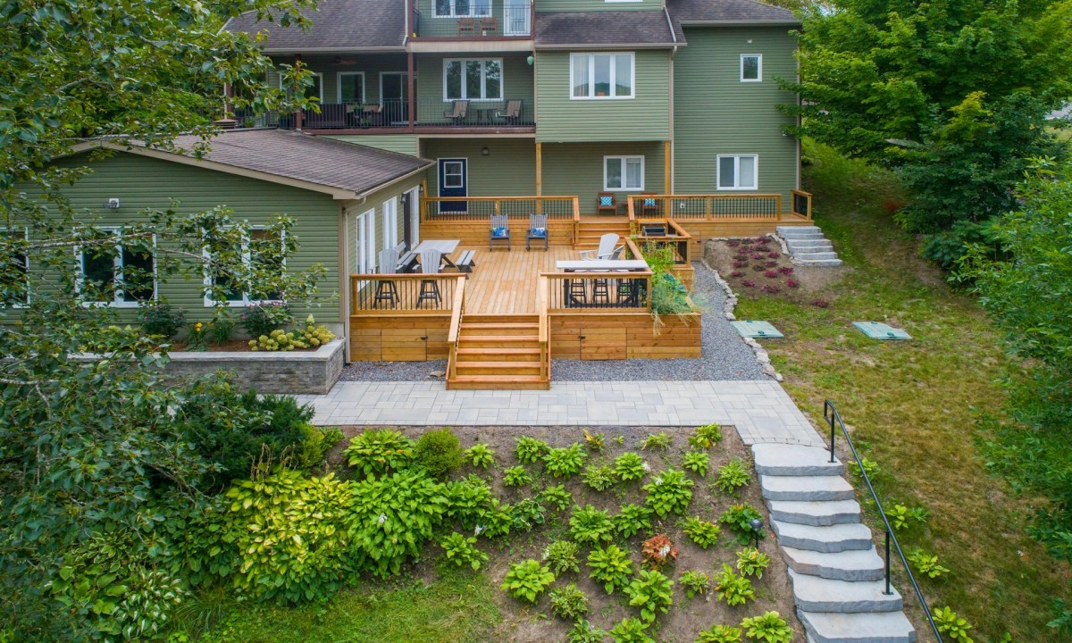 Backyard with hardscaping features like deck, stone steps, and retaining wall