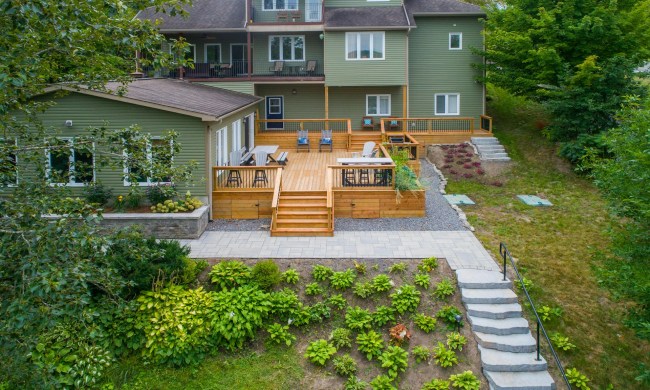 Backyard with hardscaping features like deck, stone steps, and retaining wall