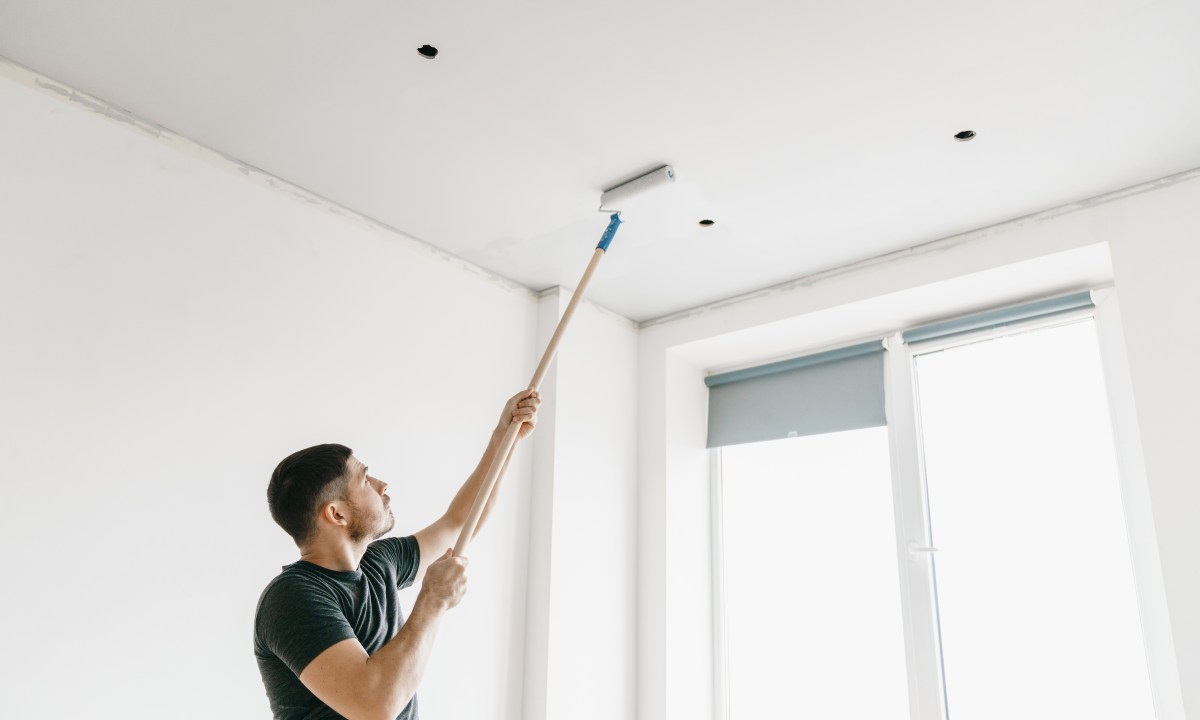Man using a roller to paint the ceiling