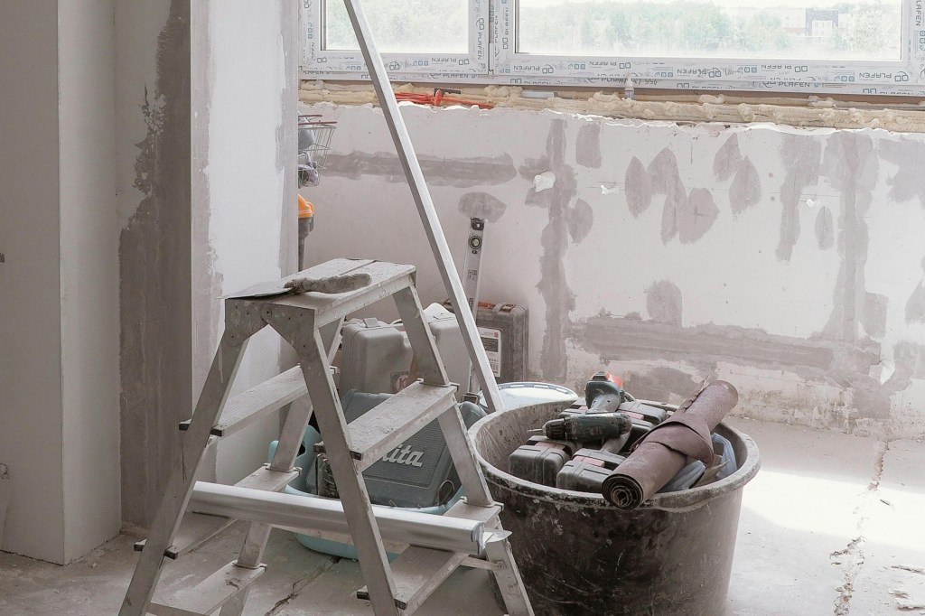 ladder and tools in front of patched drywall with spackle
