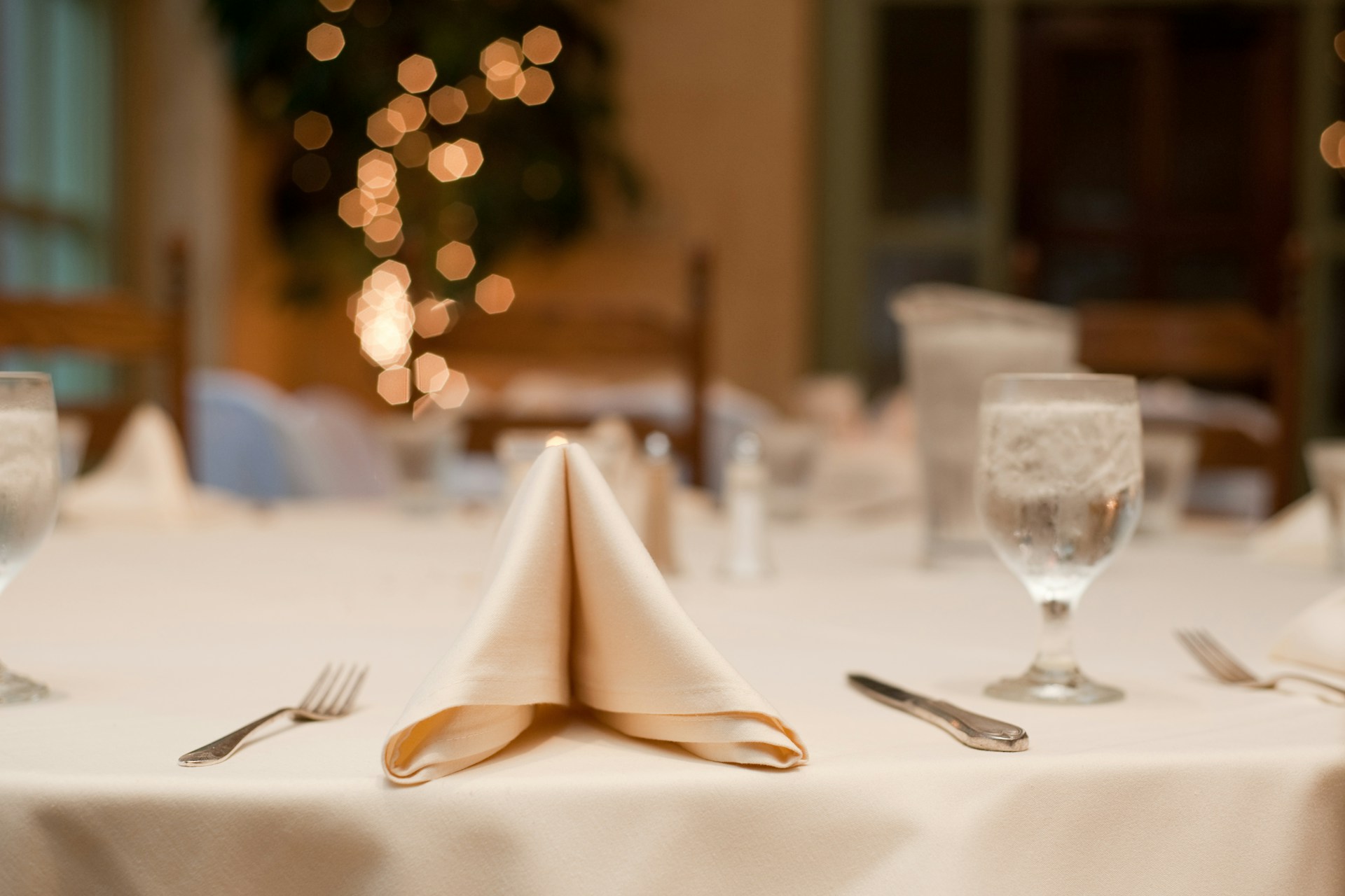 Formal dinner table with white tablecloth and folded napkins