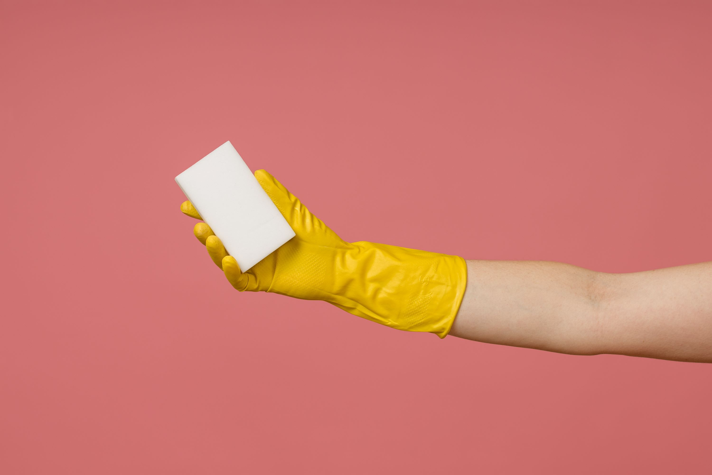 Rubber glove holds a melamine white sponge